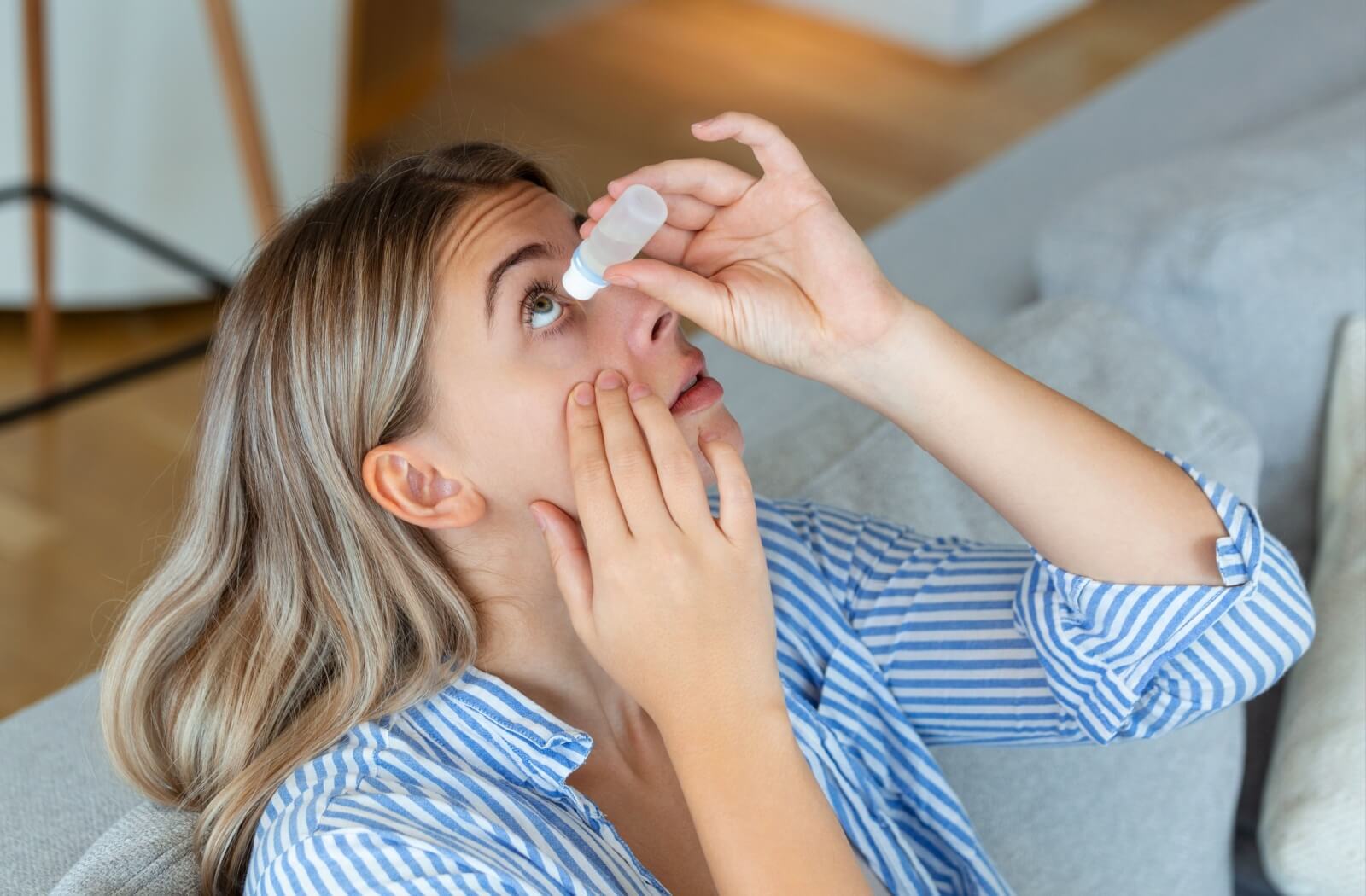 Person using eye drops at home.