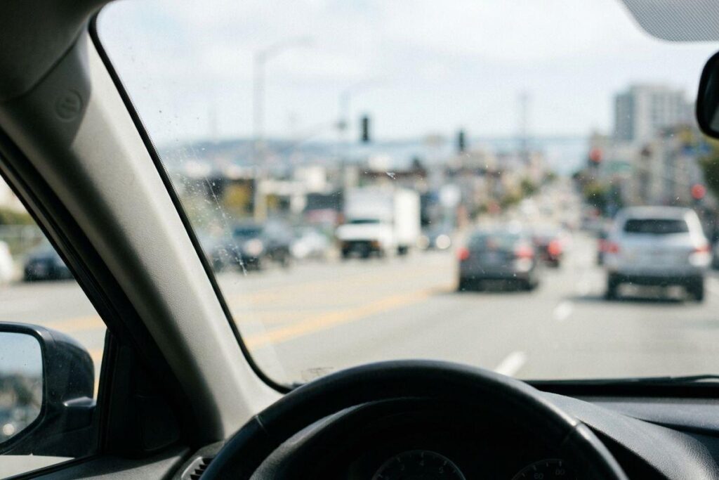 Person driving a car with an out-of-focus view of the road and steering wheel, representing blurry vision while driving